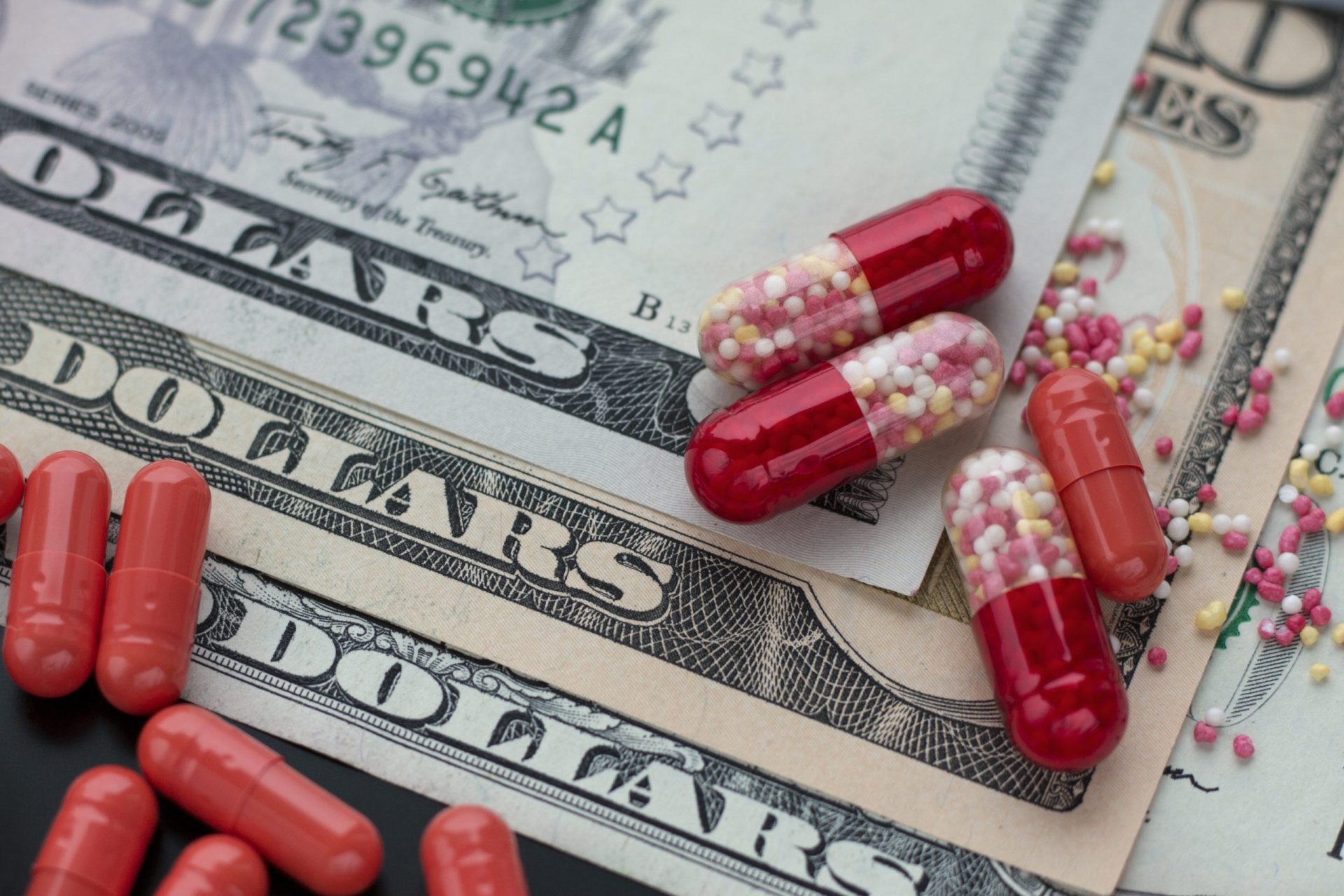 Red capsules or pills on dollar bills.  Pharmacy business.