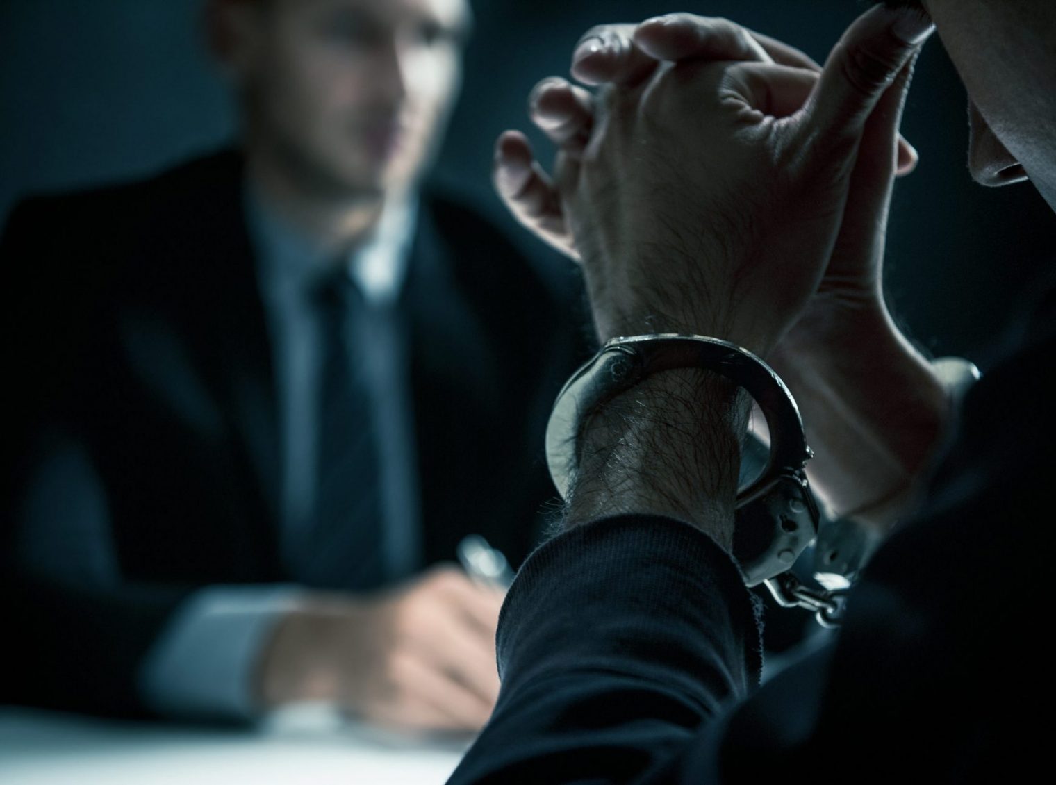 Criminal man with handcuffs in interrogation room feeling guilty after committed a crime